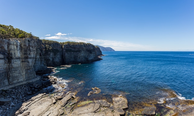 Breathtaking high angle shot of the cliffs near the pure water of Eaglehawk Neck in Australia