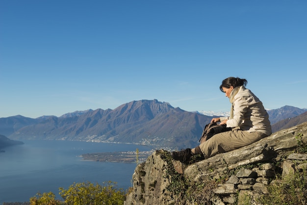 Breathtaking scene of a female sitting on the top of the mountain