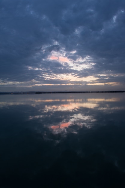 Breathtaking scenery of the sunset sky with storm clouds reflecting on the water surface