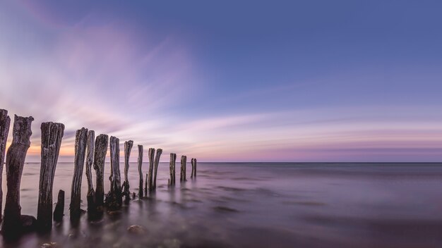 Breathtaking scenery of wooden sticks in the middle of the ocean under the colorful sky