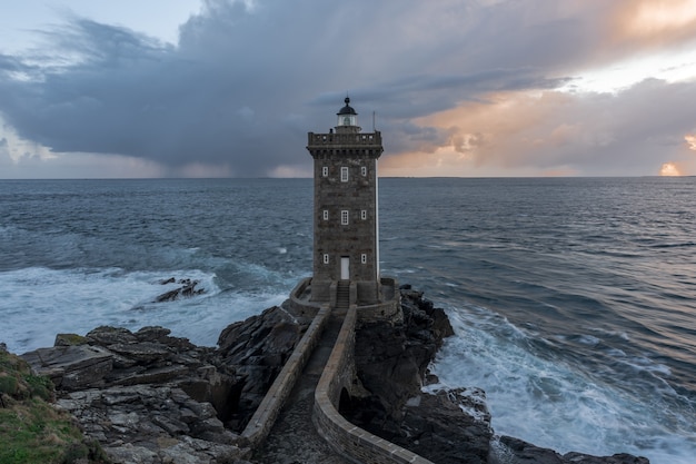 Breathtaking shot of a beautiful lighthouse standing at the seashore under the cloudy sky