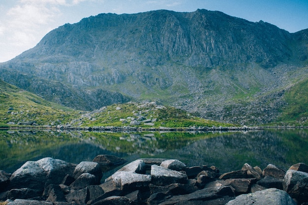 Breathtaking shot of  a crystal clear lake surrounded with rocks and high rocky mountain