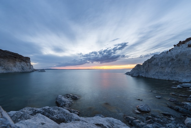 Breathtaking shot of the ocean with snowy hills on the sides and a beautiful sunset scene