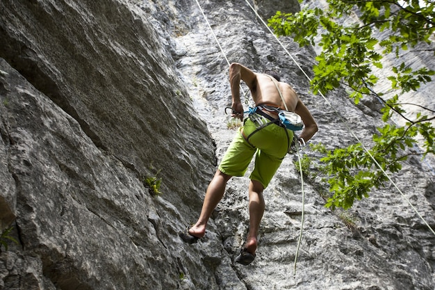 Free photo breathtaking shot of a young male climbing on the high rock in  champfromier, france