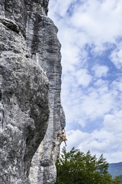 Free photo breathtaking shot of a young male climbing on the high rock in  champfromier, france