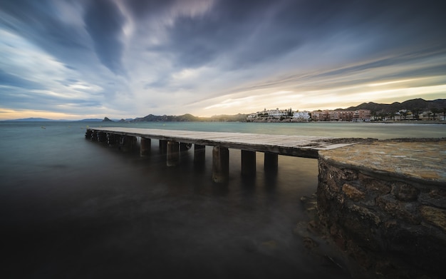 Breathtaking view of the seascape with a wooden pier at the scenic dramatic sunset