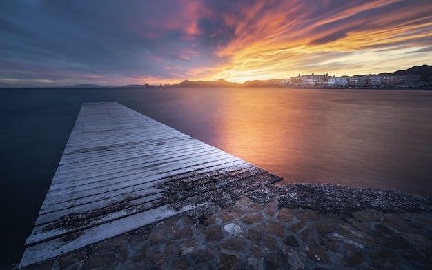 Free Photo breathtaking view of the seascape with a wooden pier at the scenic dramatic sunset