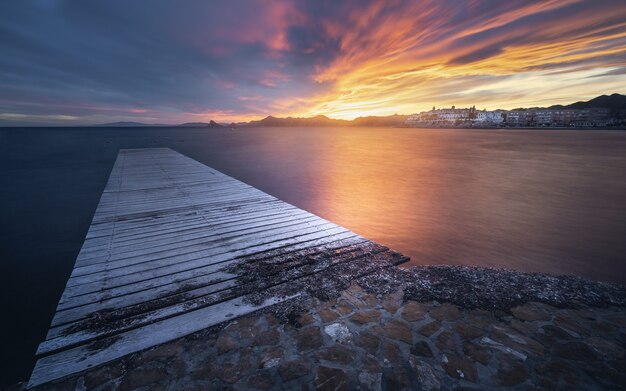 Breathtaking view of the seascape with a wooden pier at the scenic dramatic sunset