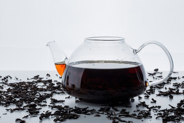 Free photo brewed tea in a glass teapot with dry black tea side view on a white surface