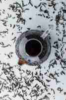 Free photo brewed tea with dry black tea in a glass teapot on white surface, top view