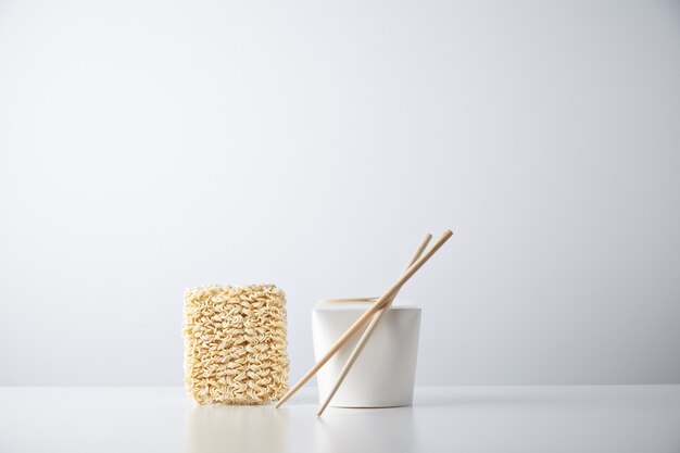 Free Photo brick of dry japanese noodles presented near closed blant retail takeaway box with chopsticks