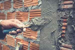 Free photo bricklaying. construction worker building a brick wall.