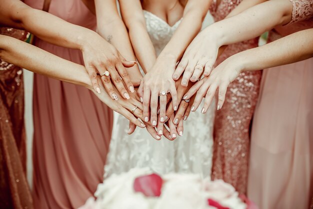 Bride and bridesmaids in pink dresses rich out their hands with