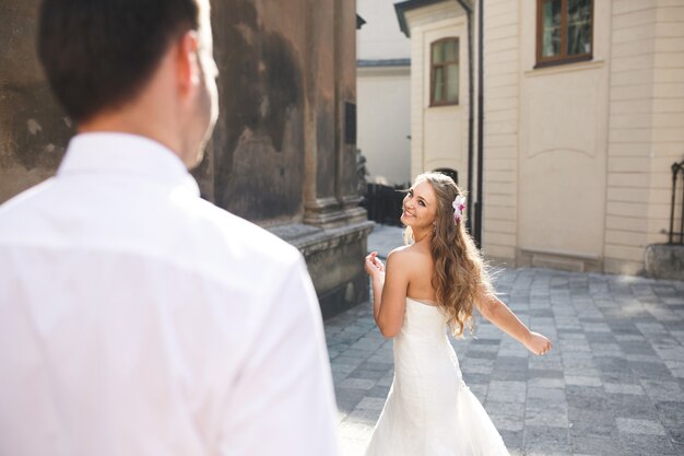 Bride dancing in the street while her husband watches