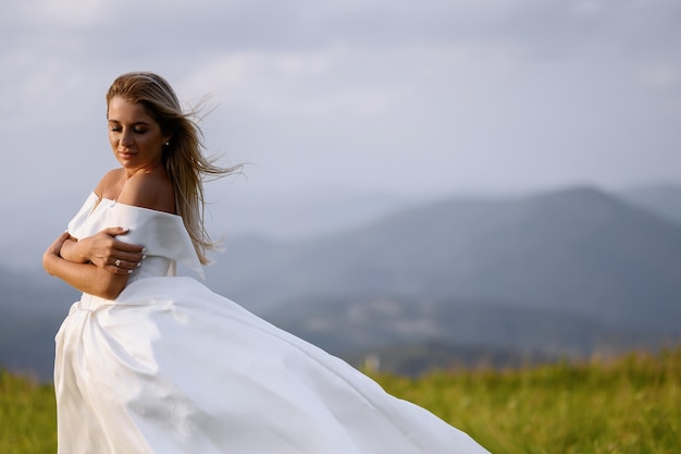 Bride Girl In White Dress Standing On Meadow With Mauntains View