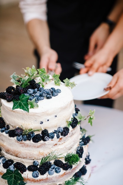 Free Photo bride and groom cut wedding cake with blueberries