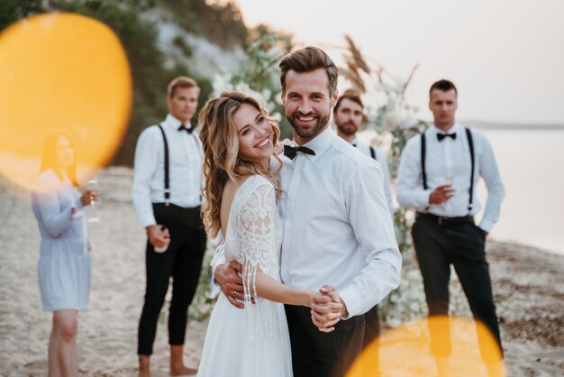 Bride and groom having their wedding with guests on a beach