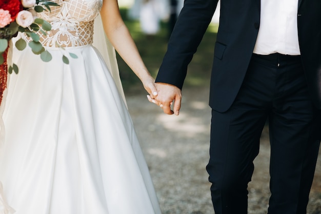 Free Photo bride and groom hold each other hands standing before the arch