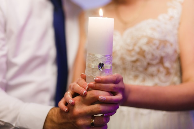 Free photo bride and groom holding candle. close-up shot of hands