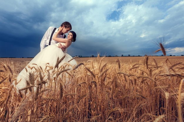 Free photo bride and groom in wheat field with dramatic sky. just married couple. wedding photography and photos. happy young fammily