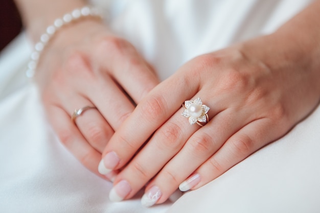 Free photo bride hand with diamond ring and pearl bracelet on white dress