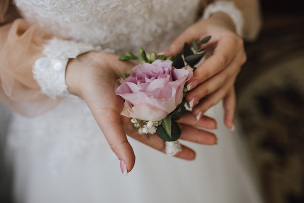 Free photo bride holds a butonholle with pink rose