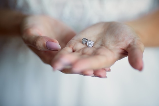 Bride holds silver earrings in her arms