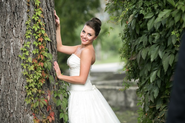 Bride leaning on a tree