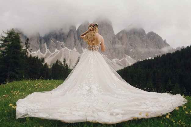 Free Photo bride in a luxury dress stands before beautiful mountain landscape 