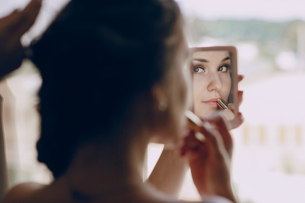 Free photo bride making  up in a small mirror