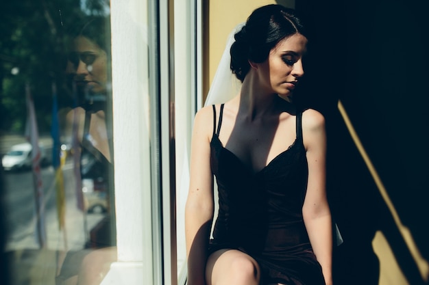 Bride in the morning sitting on the windowsill