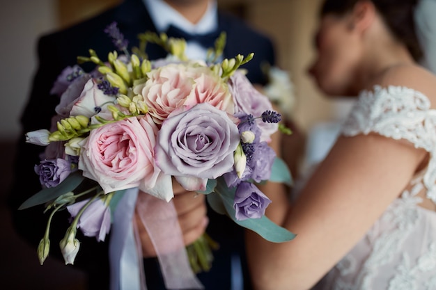 Bride pins boutonniere to groom's jacket while he holds wedding bouquet