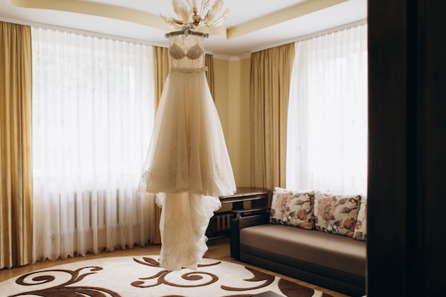 Free photo bride's dress hangs on a chandelier