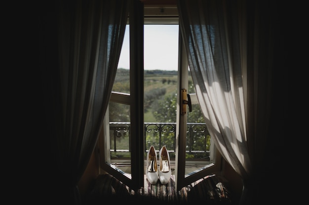 Bride's shoes stand on the windowsill with great view behind it