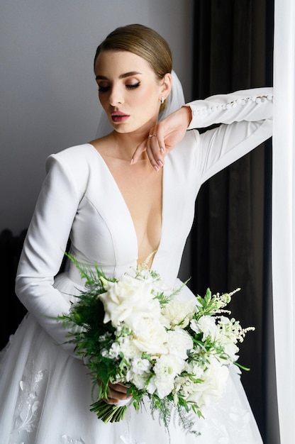 Bride in wedding gown with bouquet posing indoors