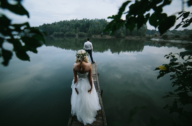 Free photo bride with her husband in front looking at a lake