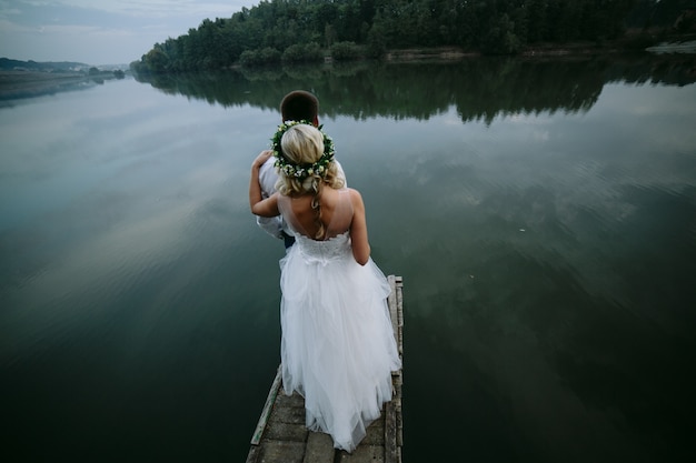 Free Photo bride with her husband in front looking at a lake