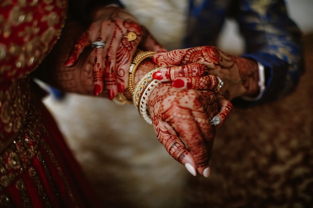 Bridesmaid helps the Indian bride put jewelry on her hand