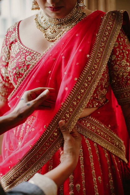 Bridesmaid helps to wear the traditional Indian bride dress