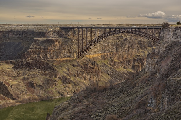 Free photo bridge in the middle of cliffs with a cloudy sky