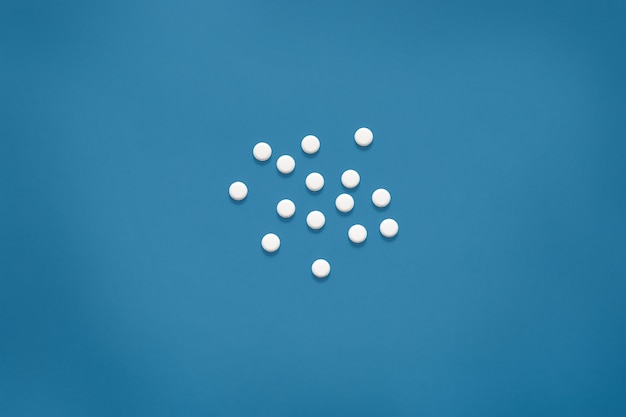 Bright blue surface with white tablets. Mock up, white pills on blue, copy space for special offers as advertising, web or other ideas. Medical, pharmacy and healthcare concept.