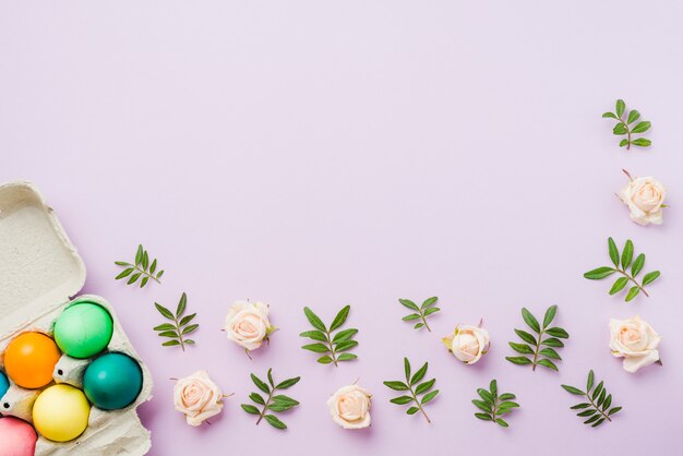 Bright collection of colored eggs in container near flowers and plant