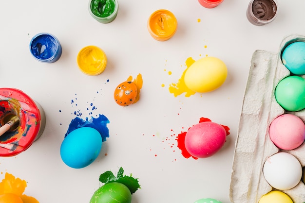 Free photo bright colored eggs near container, brush in can and water colors