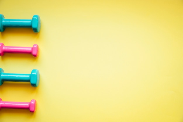 Free photo bright dumbbells on yellow background