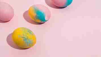 Free photo bright easter eggs scattered on pink table