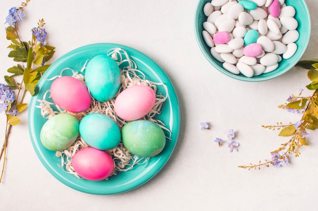 Free photo bright eggs on plate near little stones in bowl and flower twigs