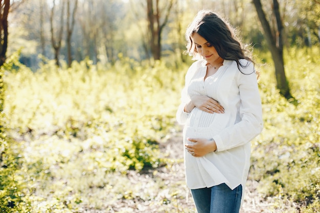 bright and happy pregnant woman walking in the sunny park 