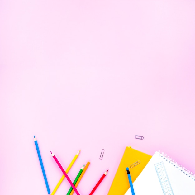 Bright pencils and notebooks laid in random way