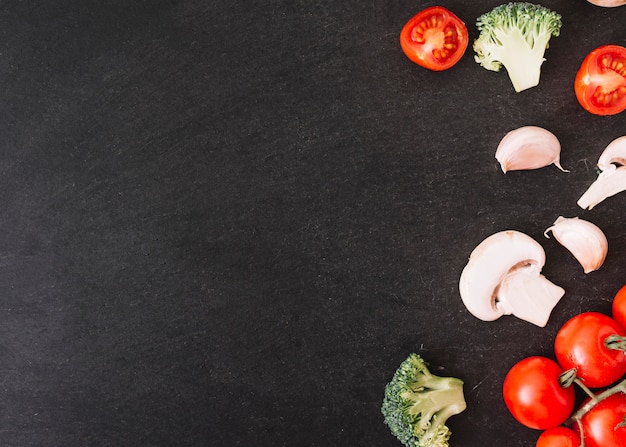 Broccoli; cherry tomatoes; mushroom and garlic cloves on white textured background