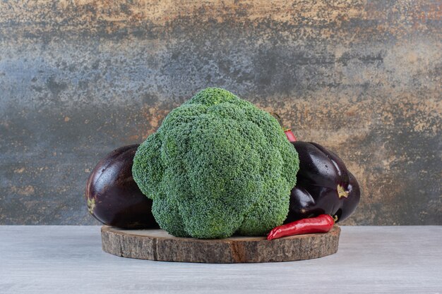 Broccoli, eggplants and peppers on wooden piece. High quality photo